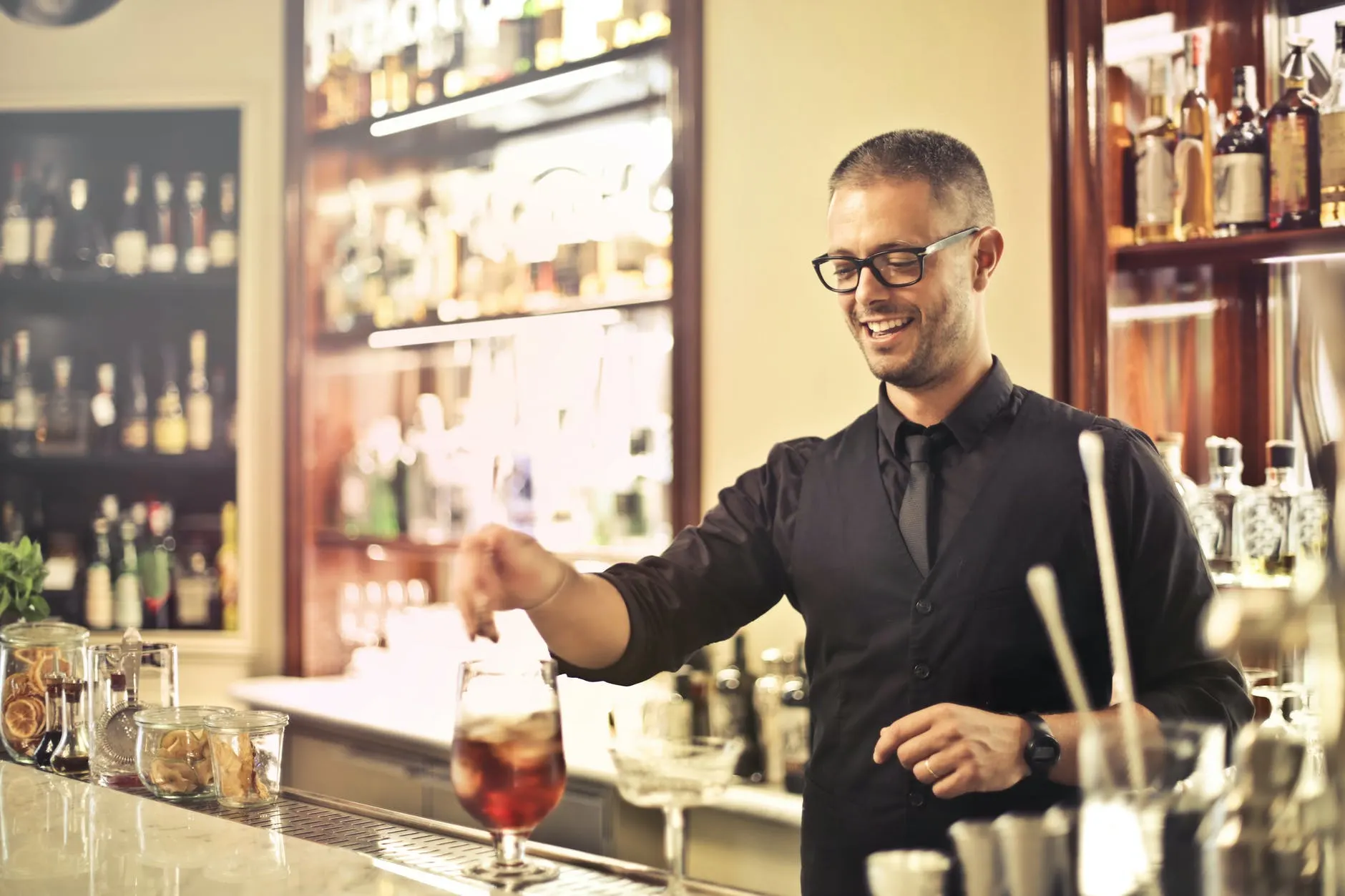 positive bartender preparing cocktail in pub
