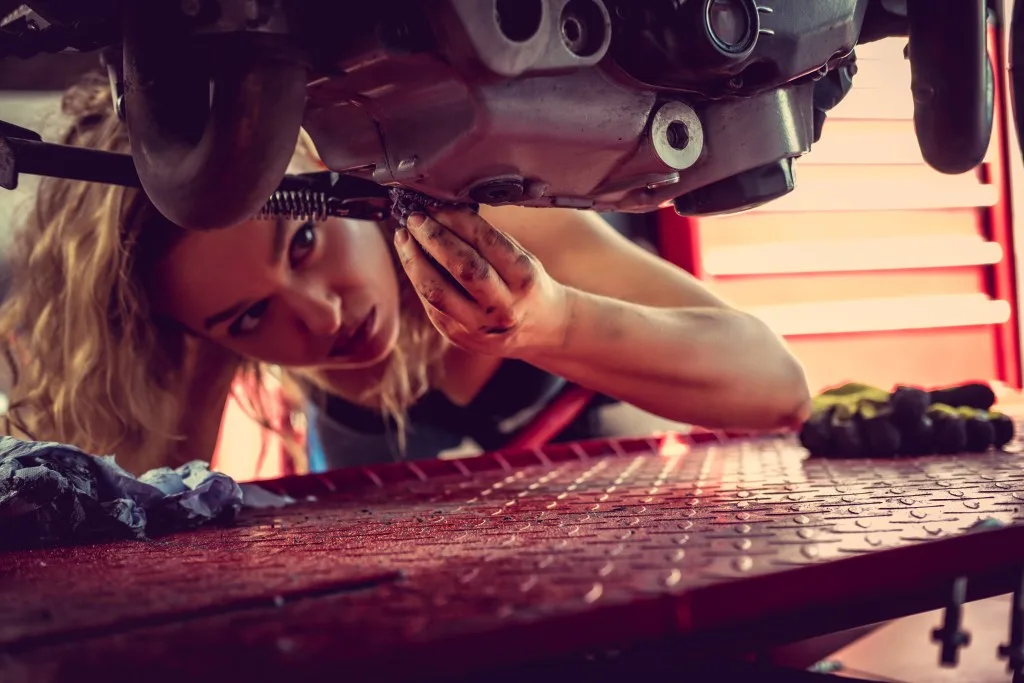 Blond female mechanic repairing vehicle. 