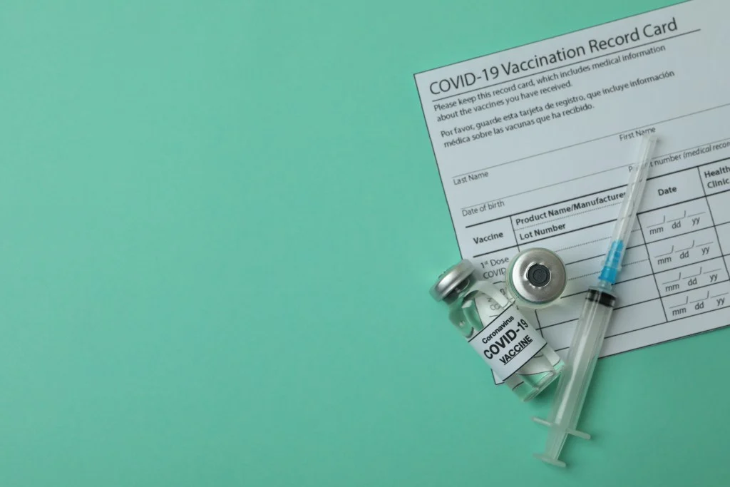 Covid-19 vaccination card and vial with vaccine.