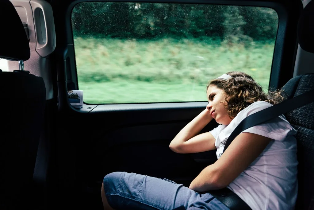 Child in RV van wearing seatbelt while falling asleep.
