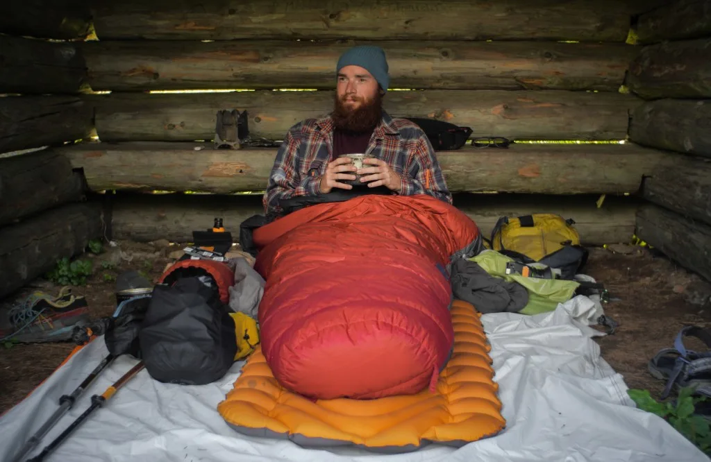 Man in sleeping bag with sleeping pad while camping.