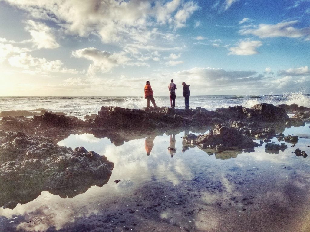 3 people overlooking ocean at Thor's Well.