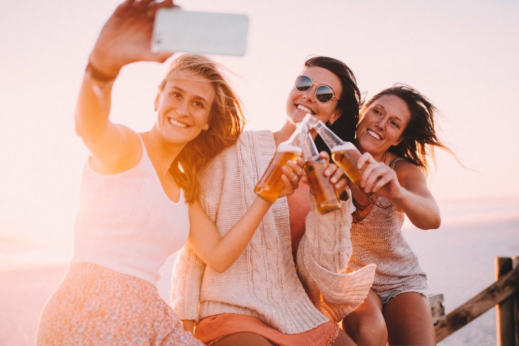 3 woman cheersing their beers.
