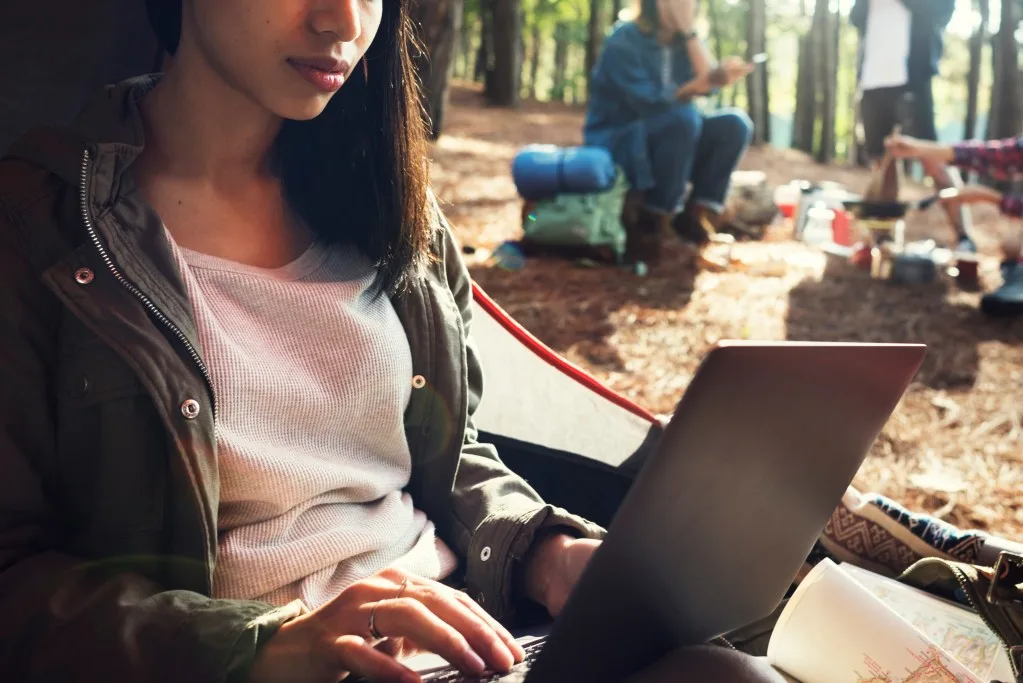 Woman camper using laptop to write review while camping.