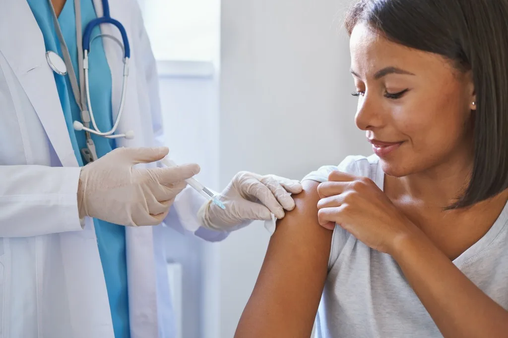 Woman receiving vaccination from doctor. 
