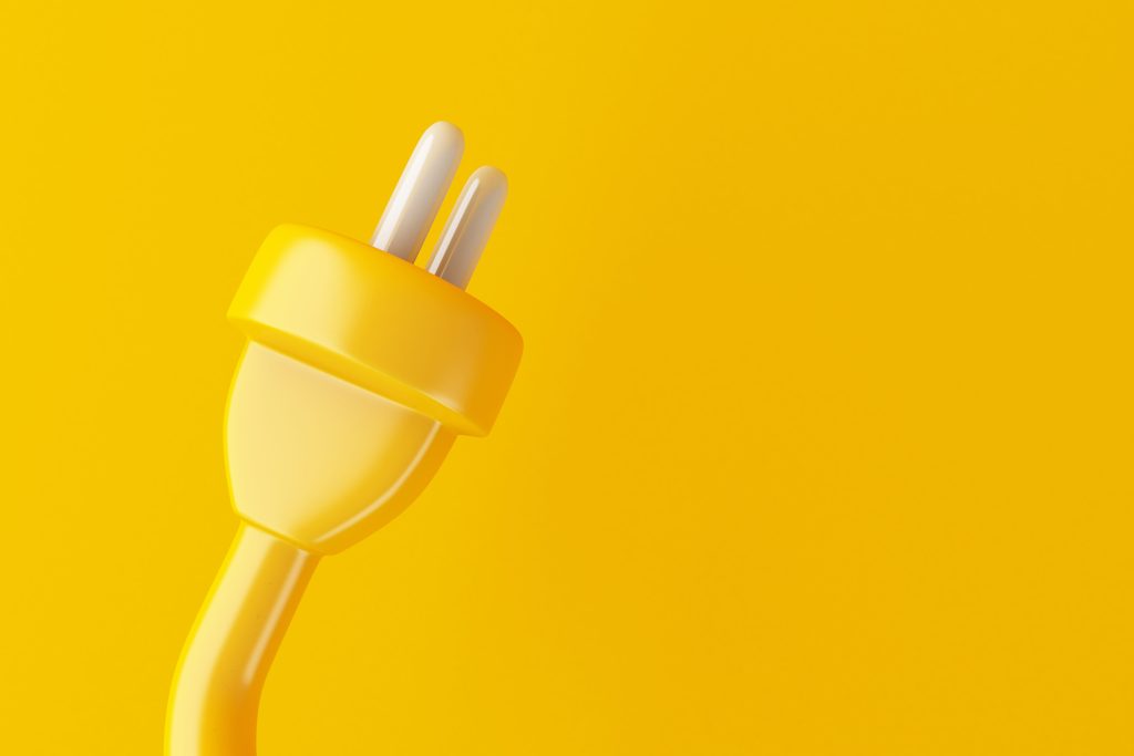 Close up of yellow 12 V plug on a yellow background.