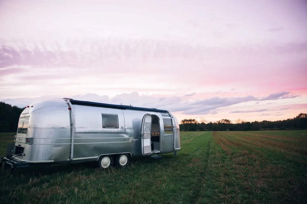 Airstream parked in a field at sunset.