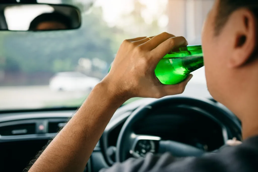 Man drinking a beer while driving his car.
