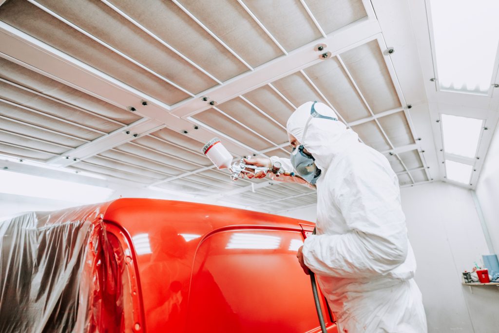 Auto mechanic painter painting a van red.