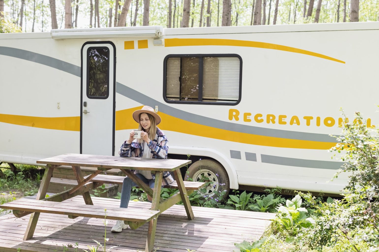Woman sitting drinking coffee in front of her RV