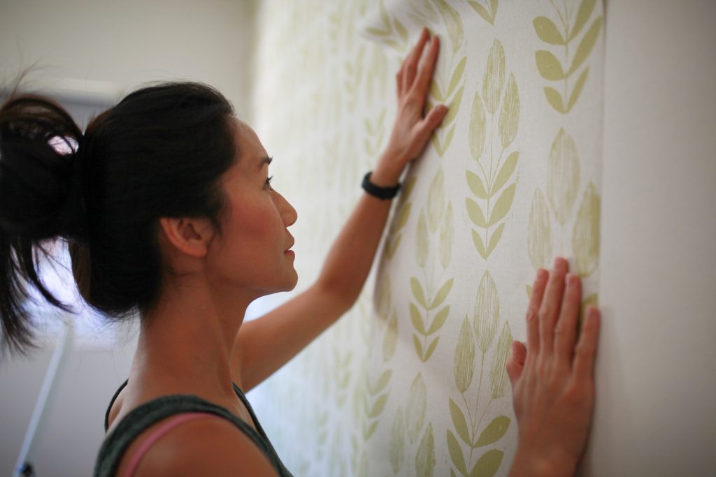 Woman hanging wall paper.