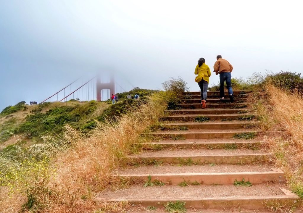 Couple hiking up stairs to the Golden Gate Bridge.