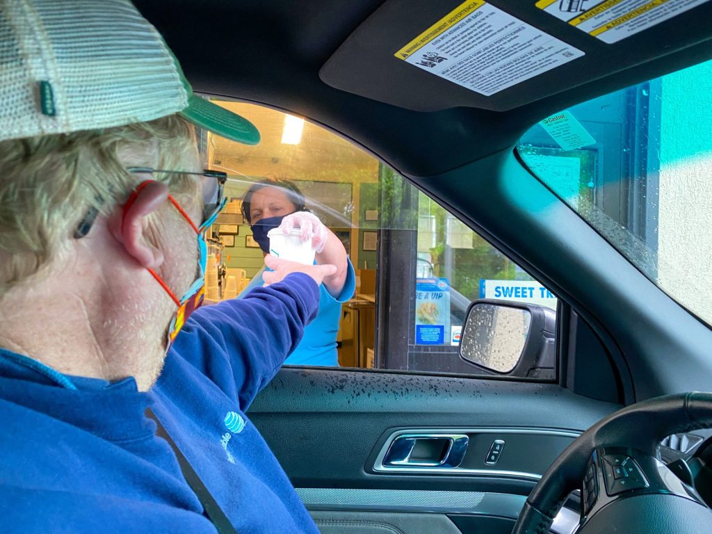 Man receiving pre-made drink through a drive-through.