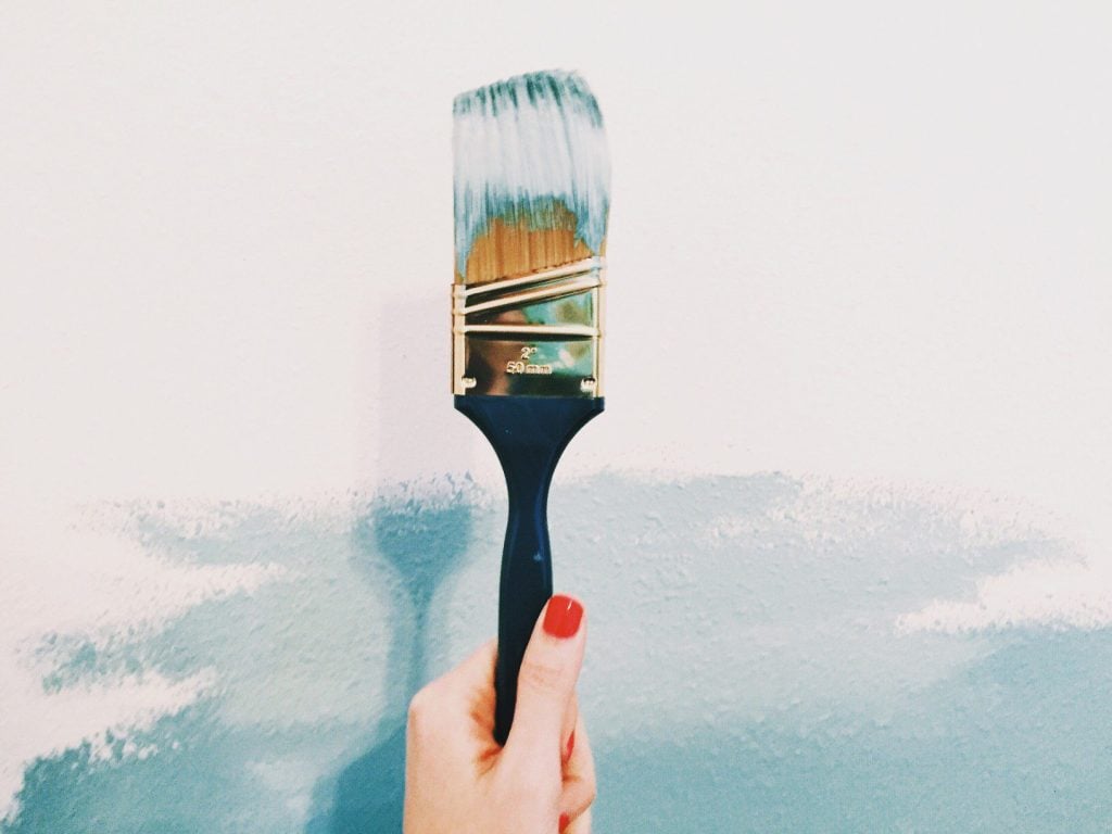 Woman's hand holding up a paint brush.