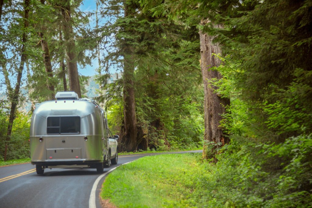 Airstream being towed through the forest.
