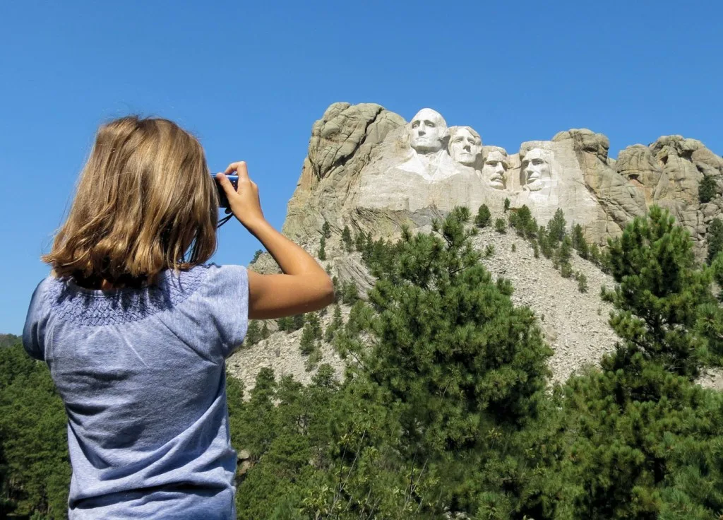Girl taking photo of Mt. Rushmore.