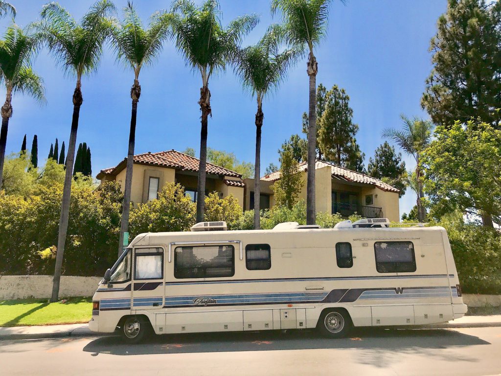 Vintage RV parked in front of house.