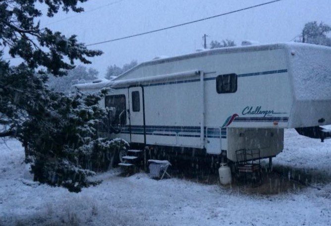 RV parked outside in the snow with no cover.