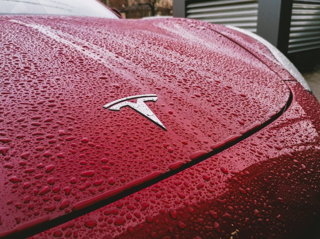 Close up of red Tesla in the rain with logo.