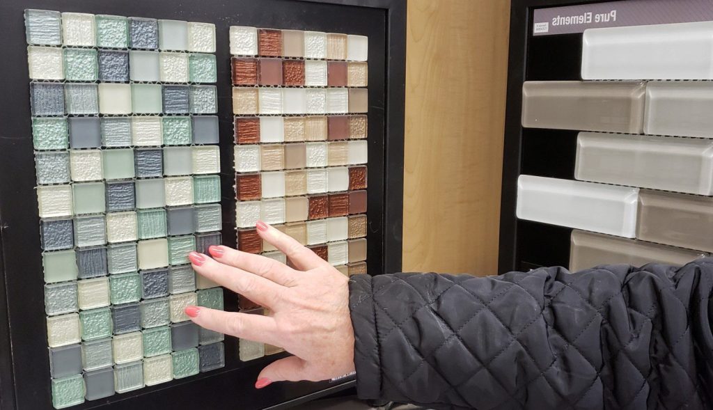 Woman's hand feeling tile when deciding what backsplash to buy.