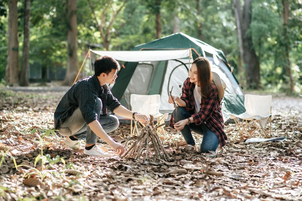 Couple using natural firewood to build a fire.