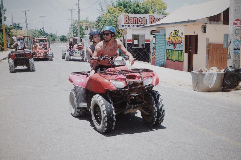 Couple riding ATV down street together.