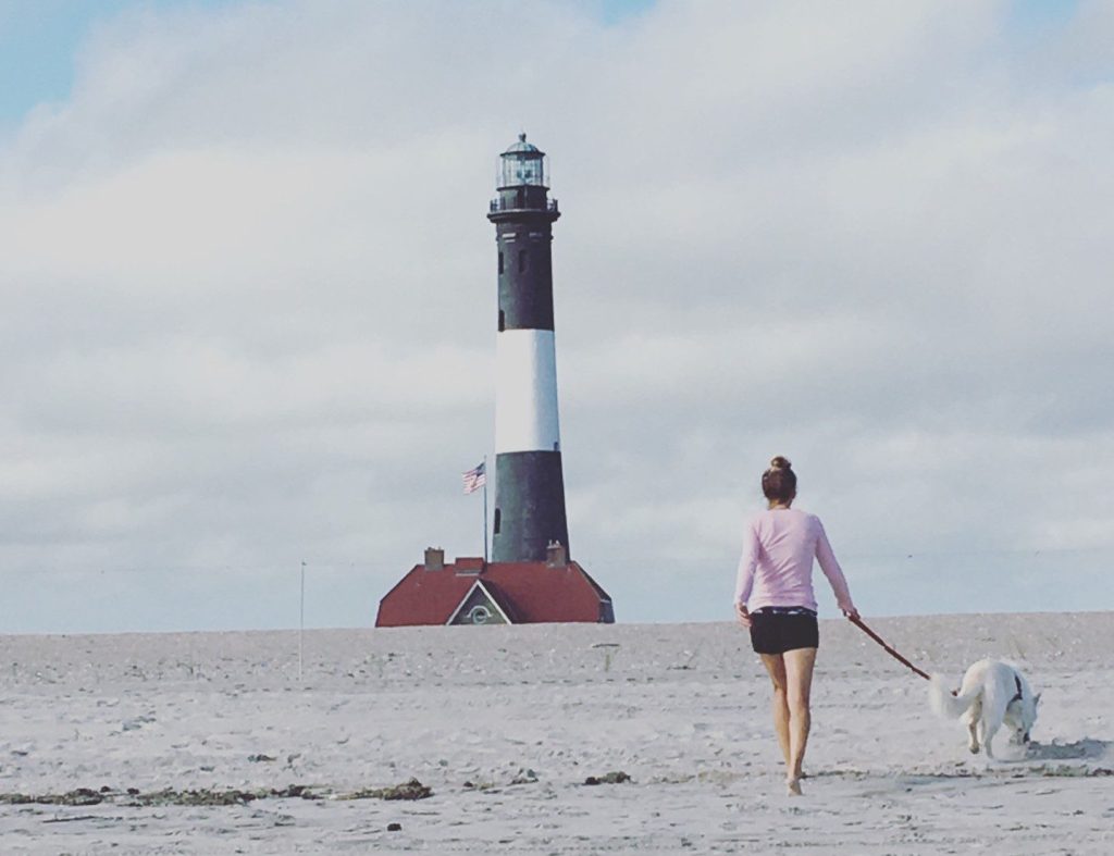 Woman walking dog by the Fire Island lighthouse.