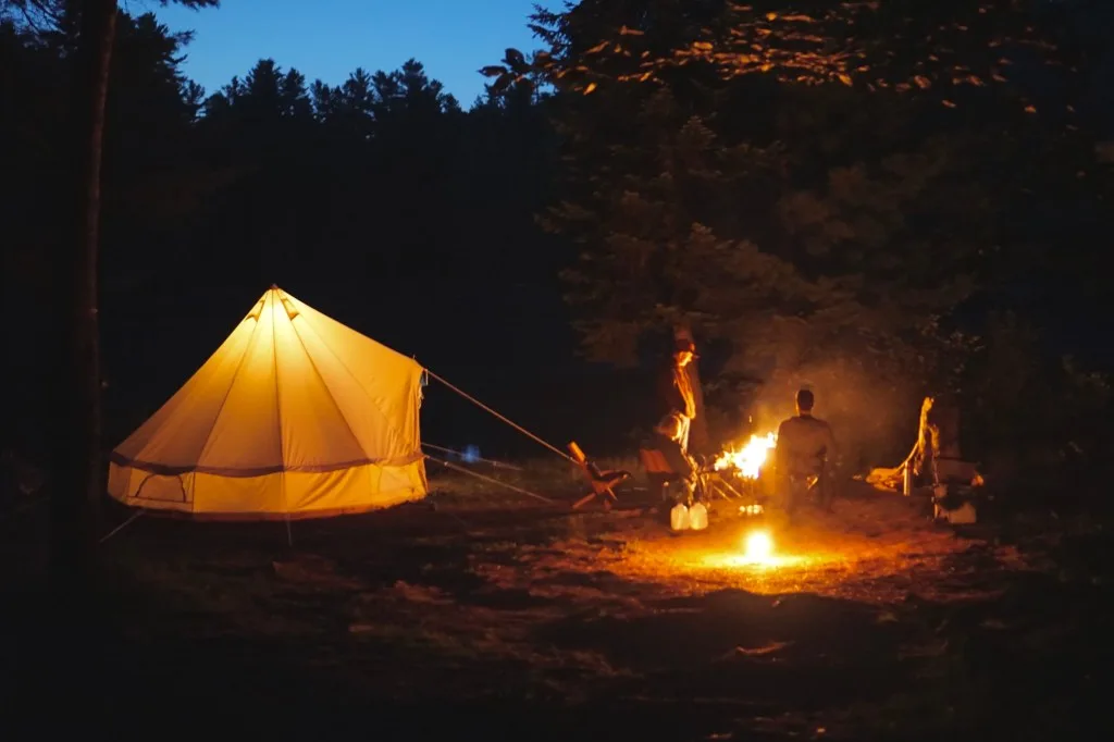 Friends sitting around campfire next to tent.