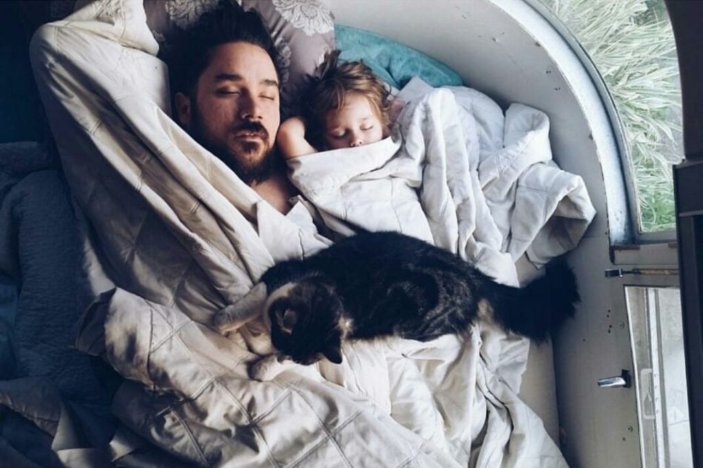 Dad, daughter, and cat sleeping in RV.