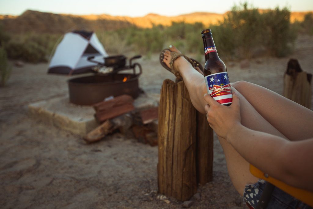 Person sitting in Mojave Desert drinking beer at a campsite.