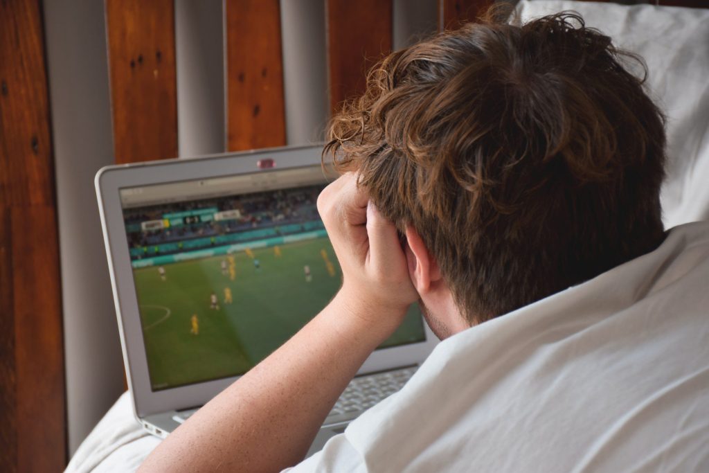 Boy streaming sports game on laptop.