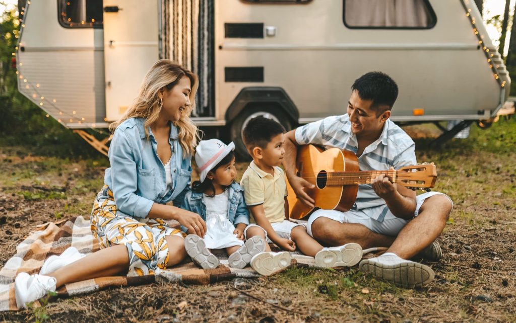 Family singing in front of teardrop camper.