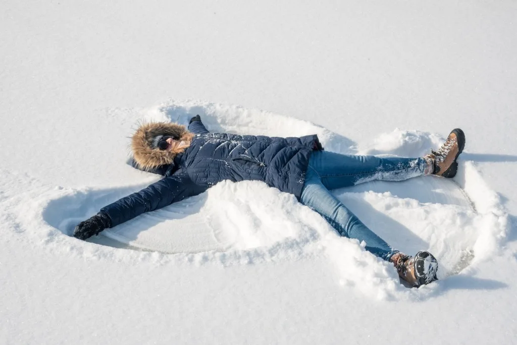 Woman making snow angels in snow.