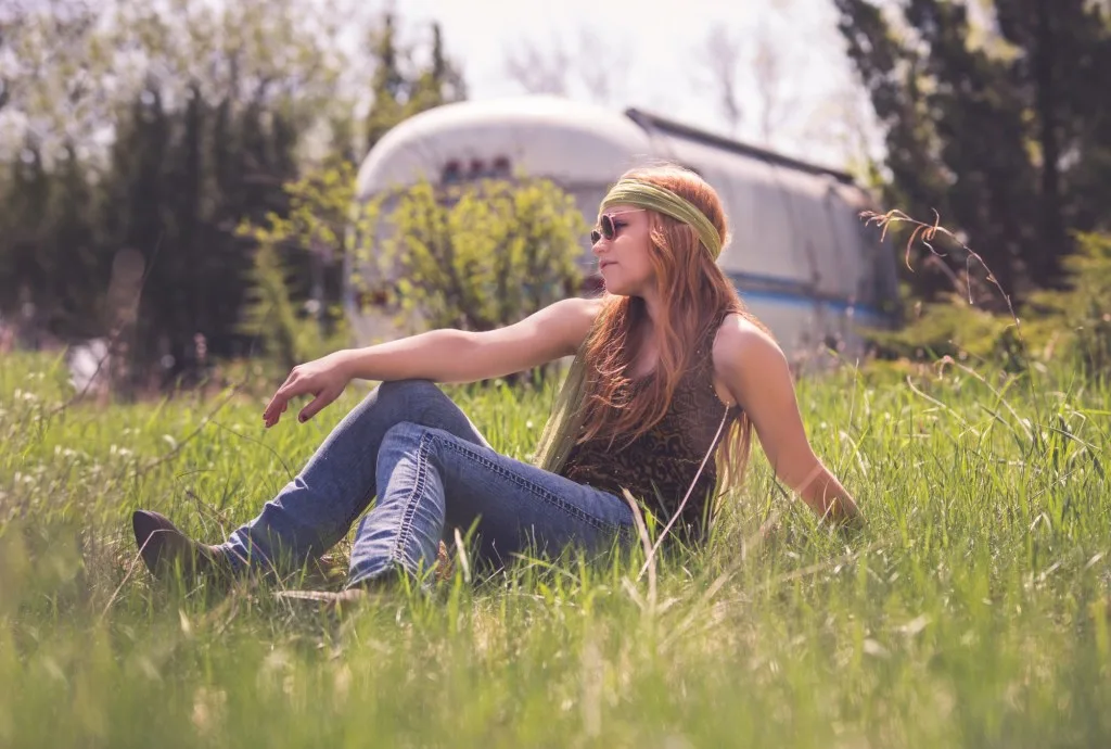 Woman posing in grass in front of an airstream.