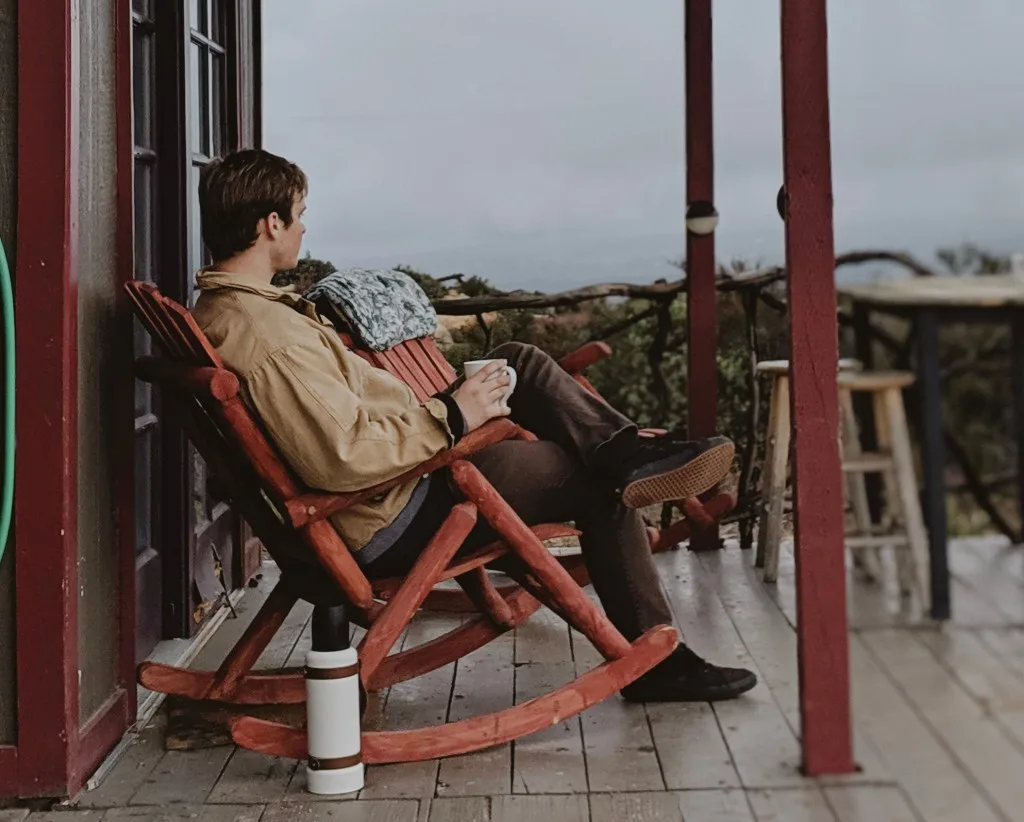 Man sitting on a rocking chair drinking coffee.