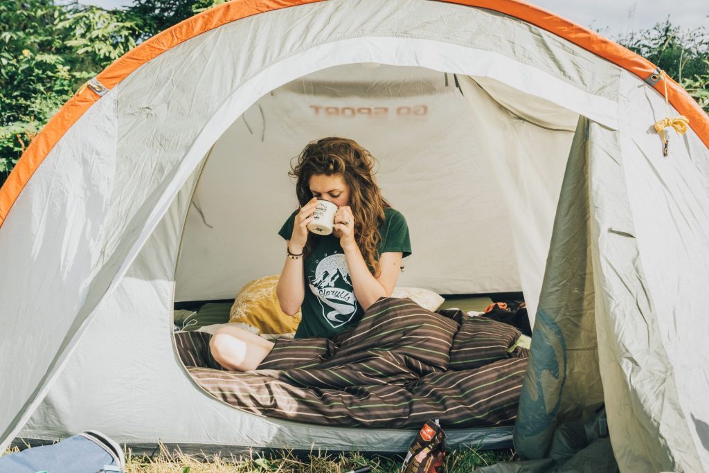 Woman drinking coffee in tent in the morning.