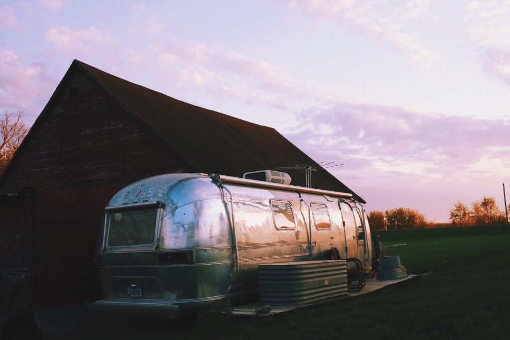 Airstream parked next to a cabin at sunset.