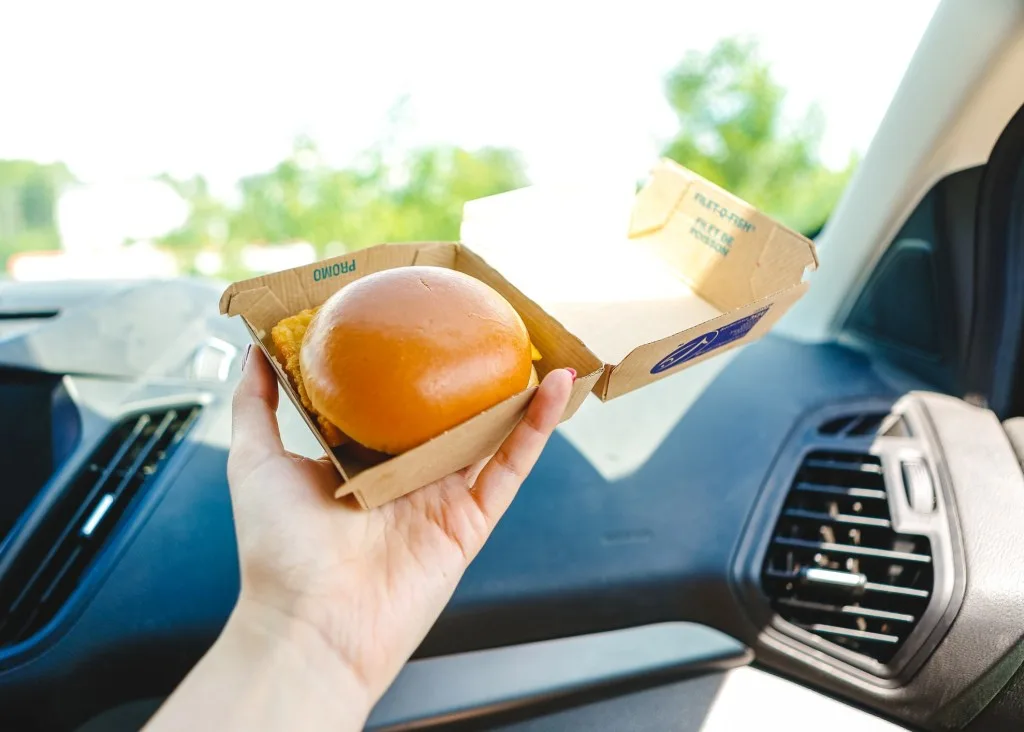 Person holding chicken sandwich in car