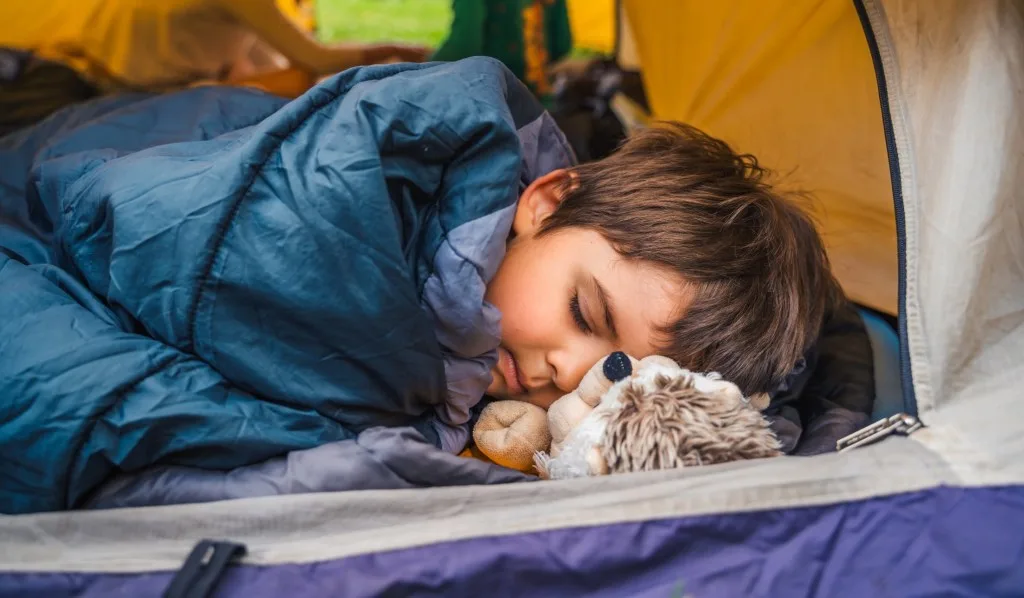 Little boy asleep in tent.