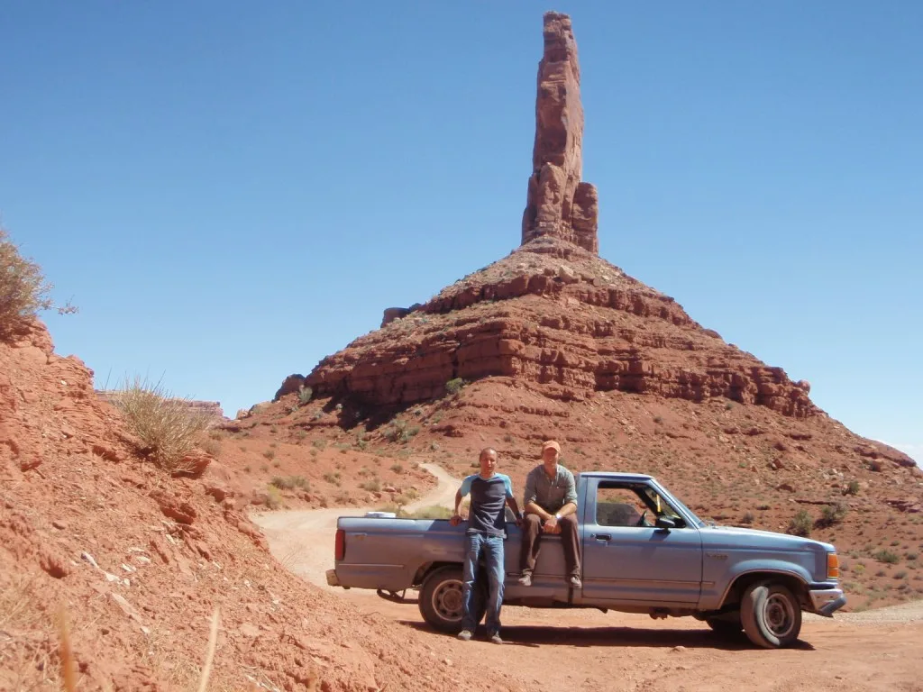 Two friends posing in desert with their pick up truck.