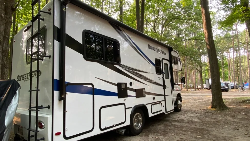 RV parked between trees at an RV campsite.