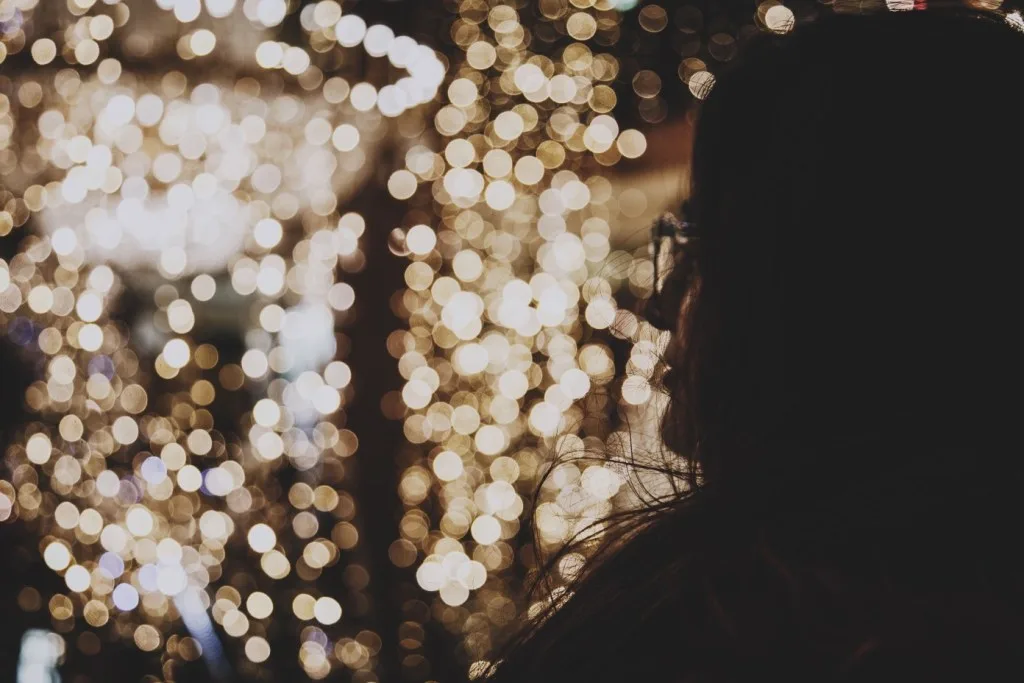 Woman standing in front of Christmas lights. 