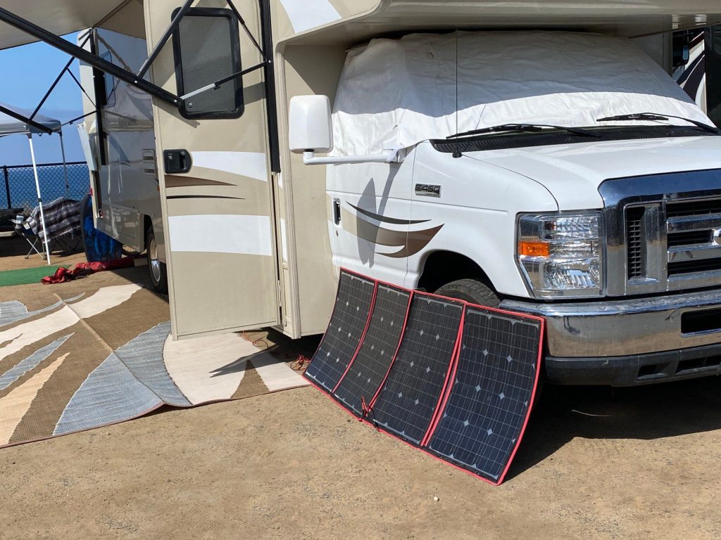 RV with solar panels set up in front of it.
