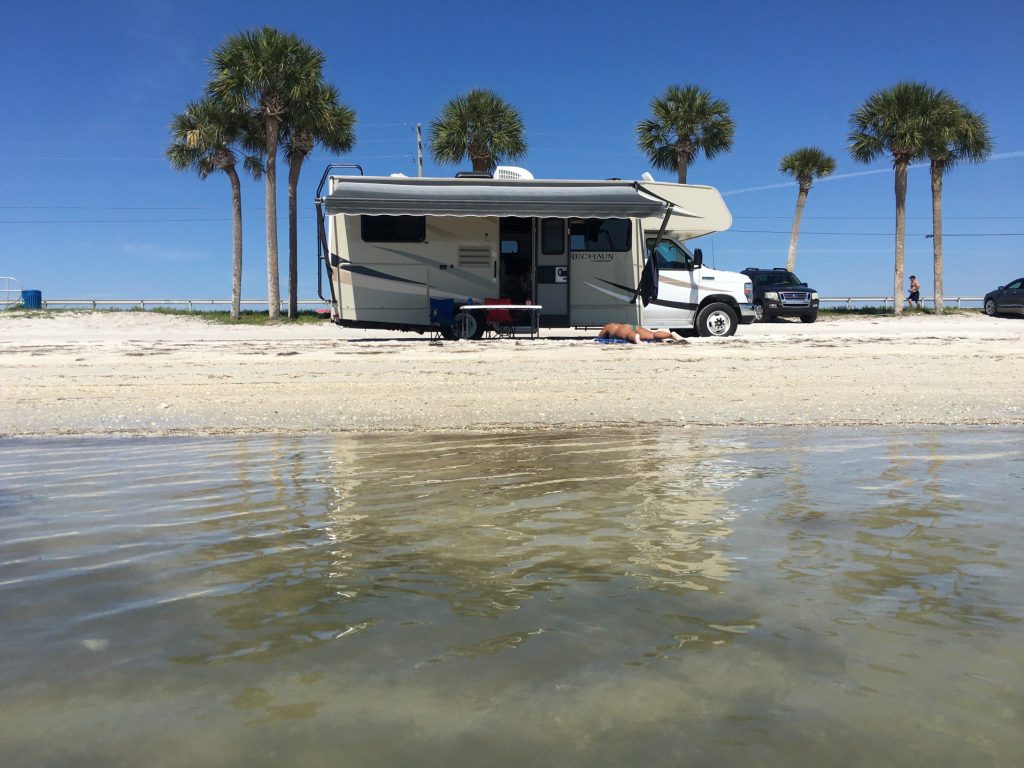 Woman tanning on beach in front of RV