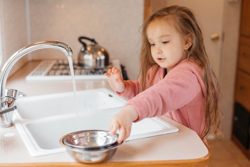Little girl using sink in RV.