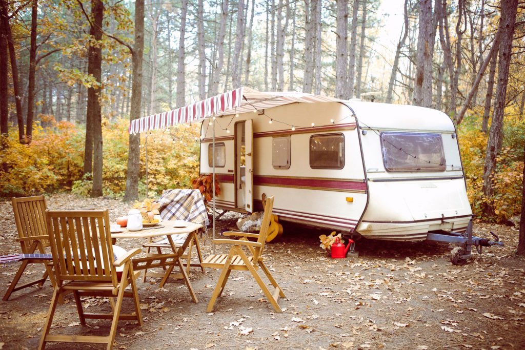Vintage camper parked at campsite in forest.