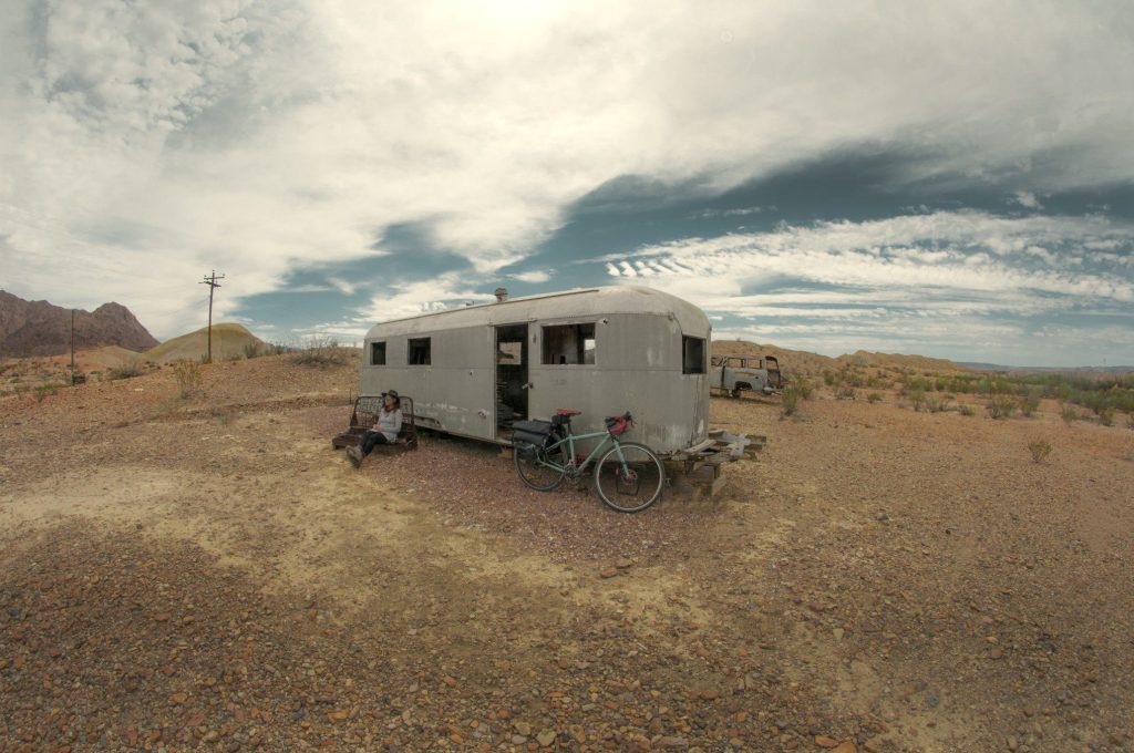 Woman sitting in front of RV parked on public land.