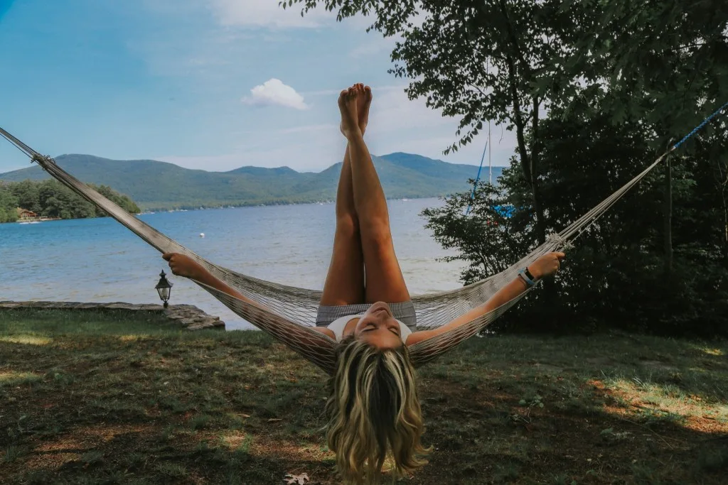 Woman relaxing in hammock by water