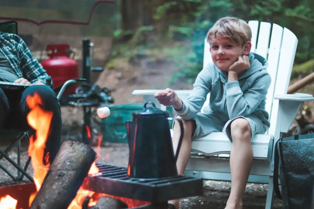 Boy roasting marshmallow at RV campsite.