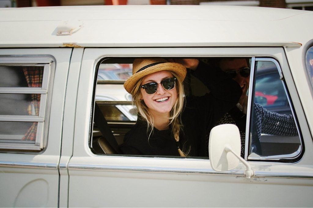 Woman happily smiling from van while on the road.